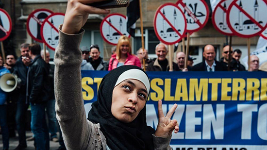 Une jeune musulmane se prend en selfie devant une manifestation islamophobe